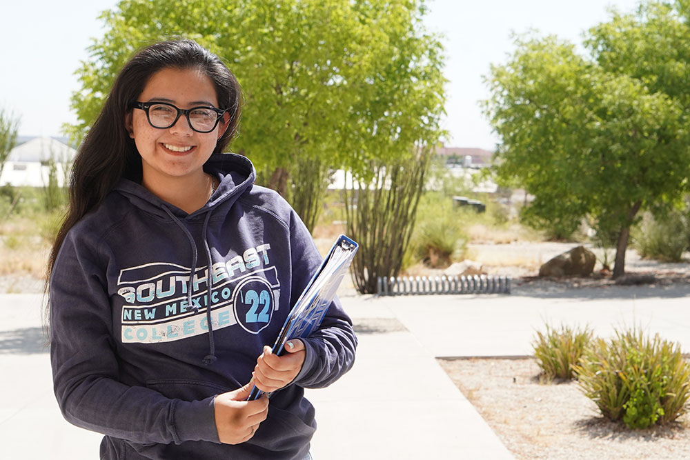 Female student outside holding a binder