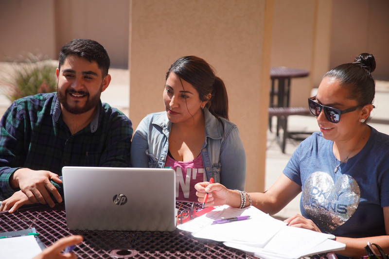 Students sitting on a table looking at a computer